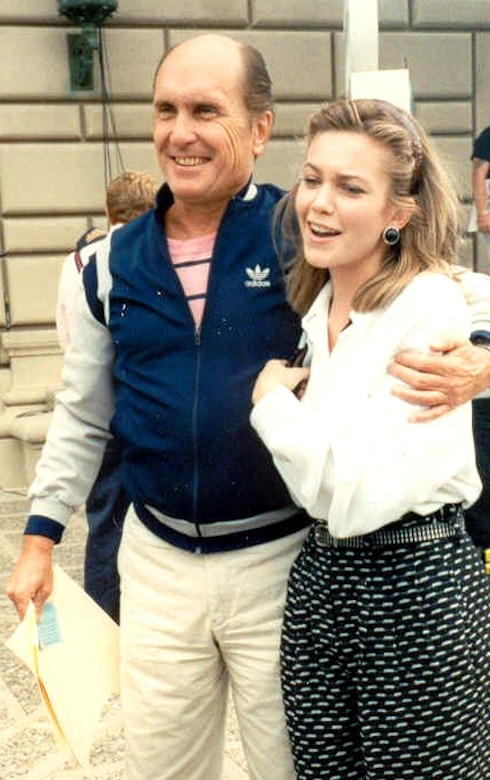 An older man has his arm around the shoulders of a young woman.
