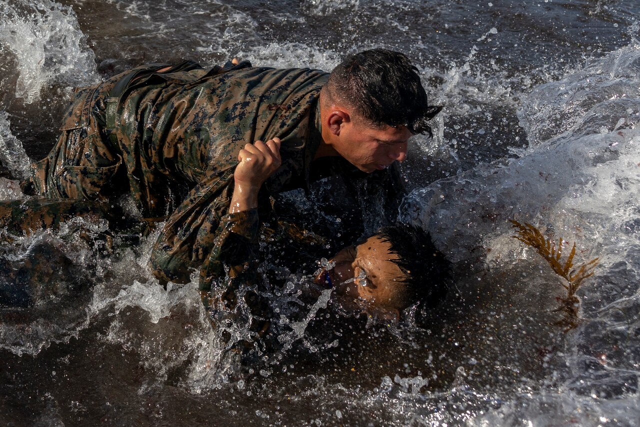 Two Marines grapple in water.