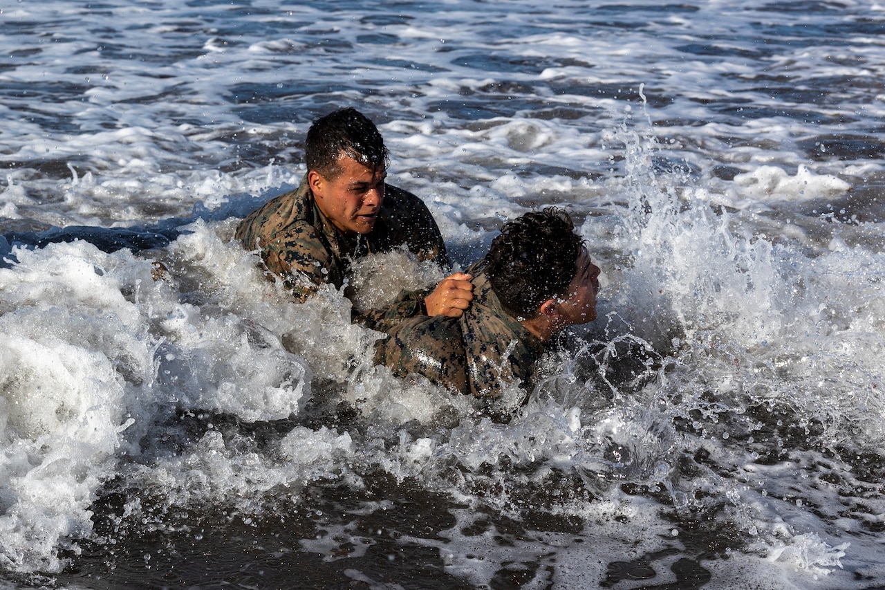 Two Marines grapple in water.