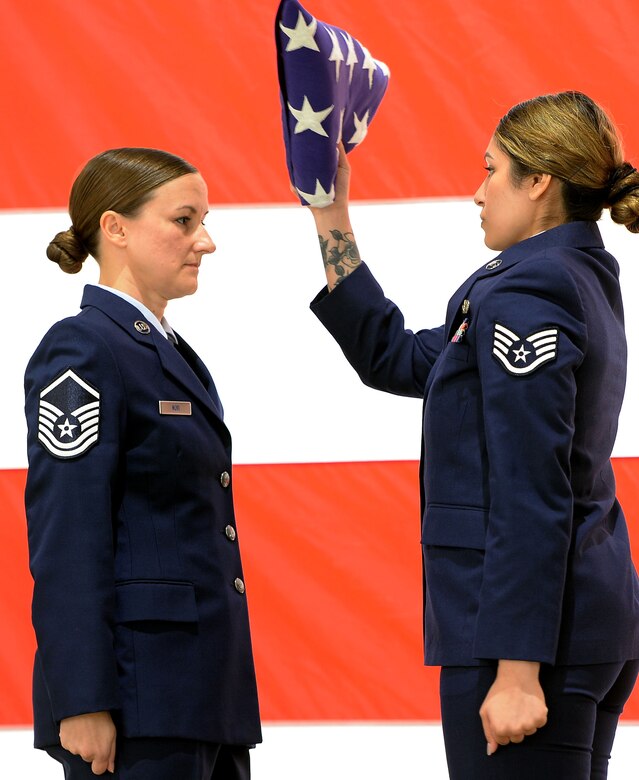 Two Airmen assist with flag fold ceremony.