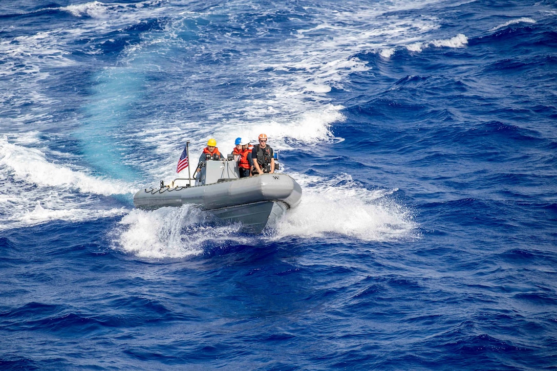 Sailors leave a wake while operating a boat in a body of water.