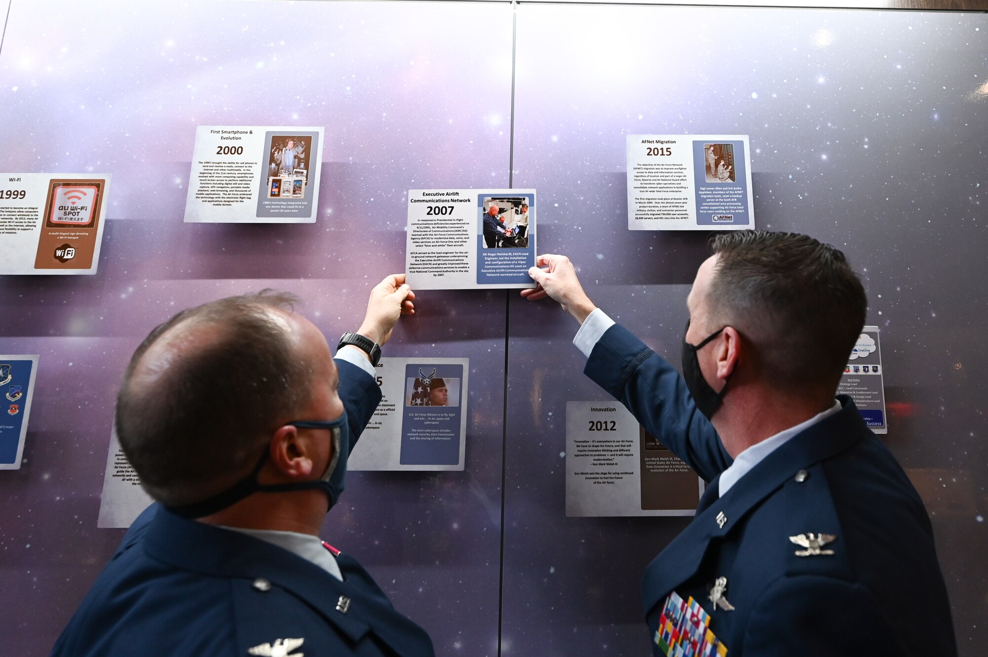 Col. Robert Kelly, Air Mobility Command director of communications and chief information officer and Col. Kevin Kirsch, HQ Cyberspace Capabilities Center commander place a plaque honoring the accomplishments of the Executive Airlift Communications Network team at the Air Force Cyberspace and Communications Heritage Center on Scott Air Force Base, Illinois, Jan. 4, 2021. The plaque now hangs on a timeline wall in the heritage center, a wall of historical accomplishments covering more than 75 years in communication history. (U.S. Air Force photo by Staff Sgt. Dalton Williams)