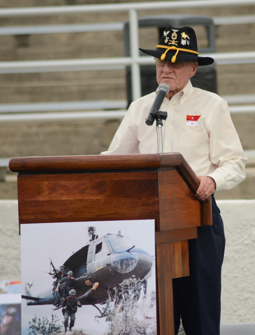 A man wearing a cavalry hat stands at a lectern.