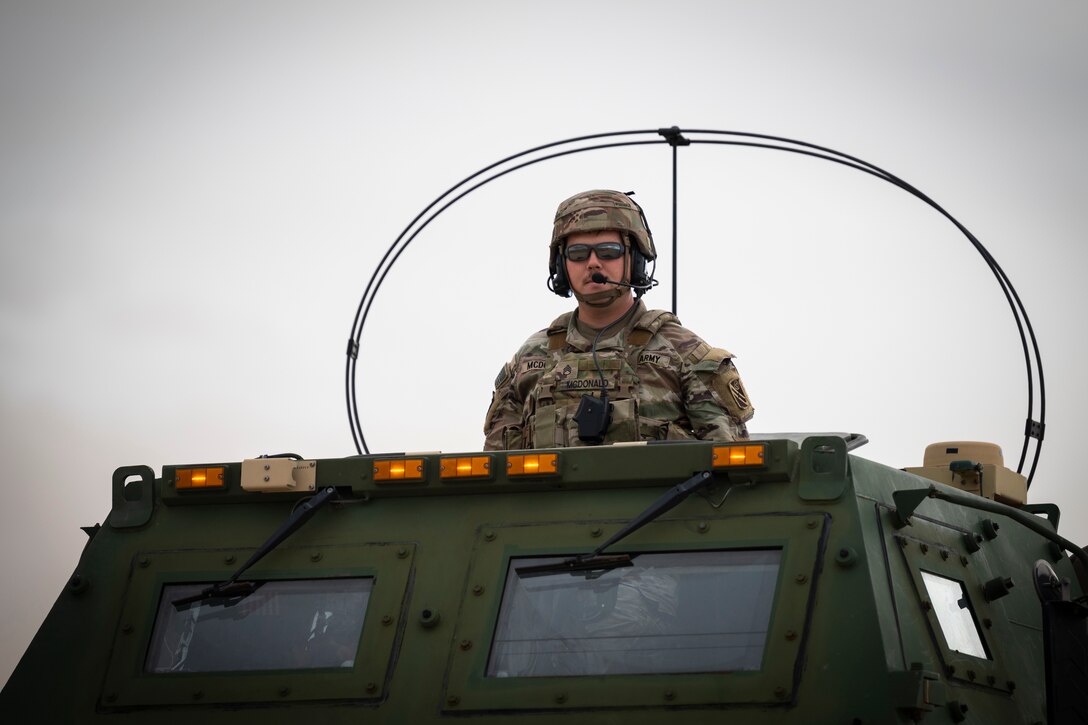 A soldier stands in a military vehicle.