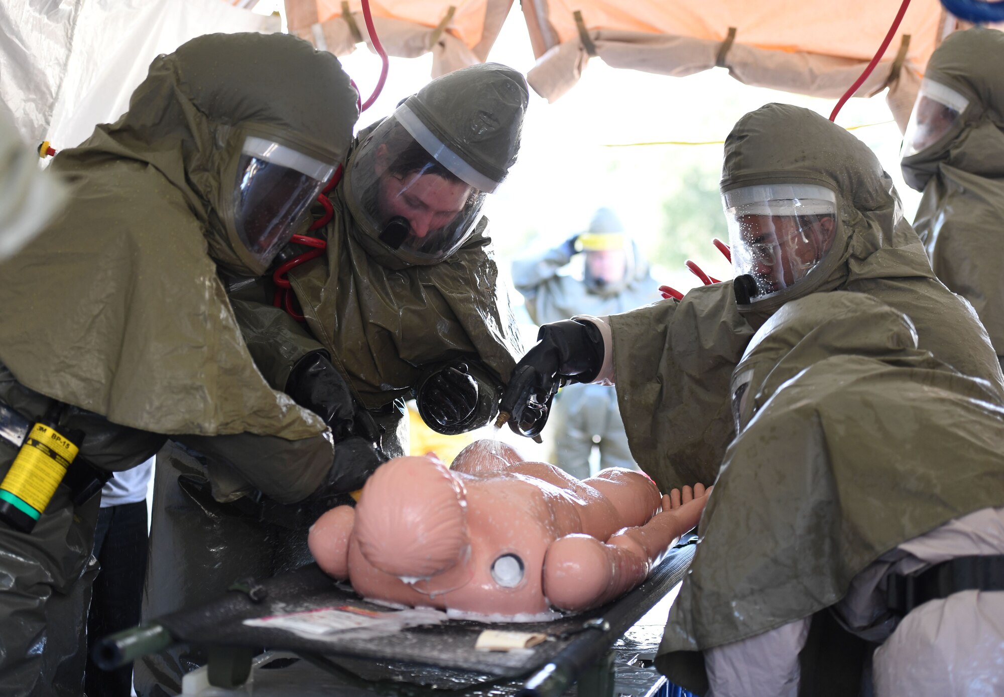 Keesler medics wash a simulated patient during a decontamination training course behind the Keesler Medical Center at Keesler Air Force Base, Mississippi, Jan. 6, 2022. The course provided the tools and skills necessary to maintain an effective level of decontamination operational ability in the event of a chemical, biological, radiological or nuclear incident. (U.S. Air Force photo by Kemberly Groue)