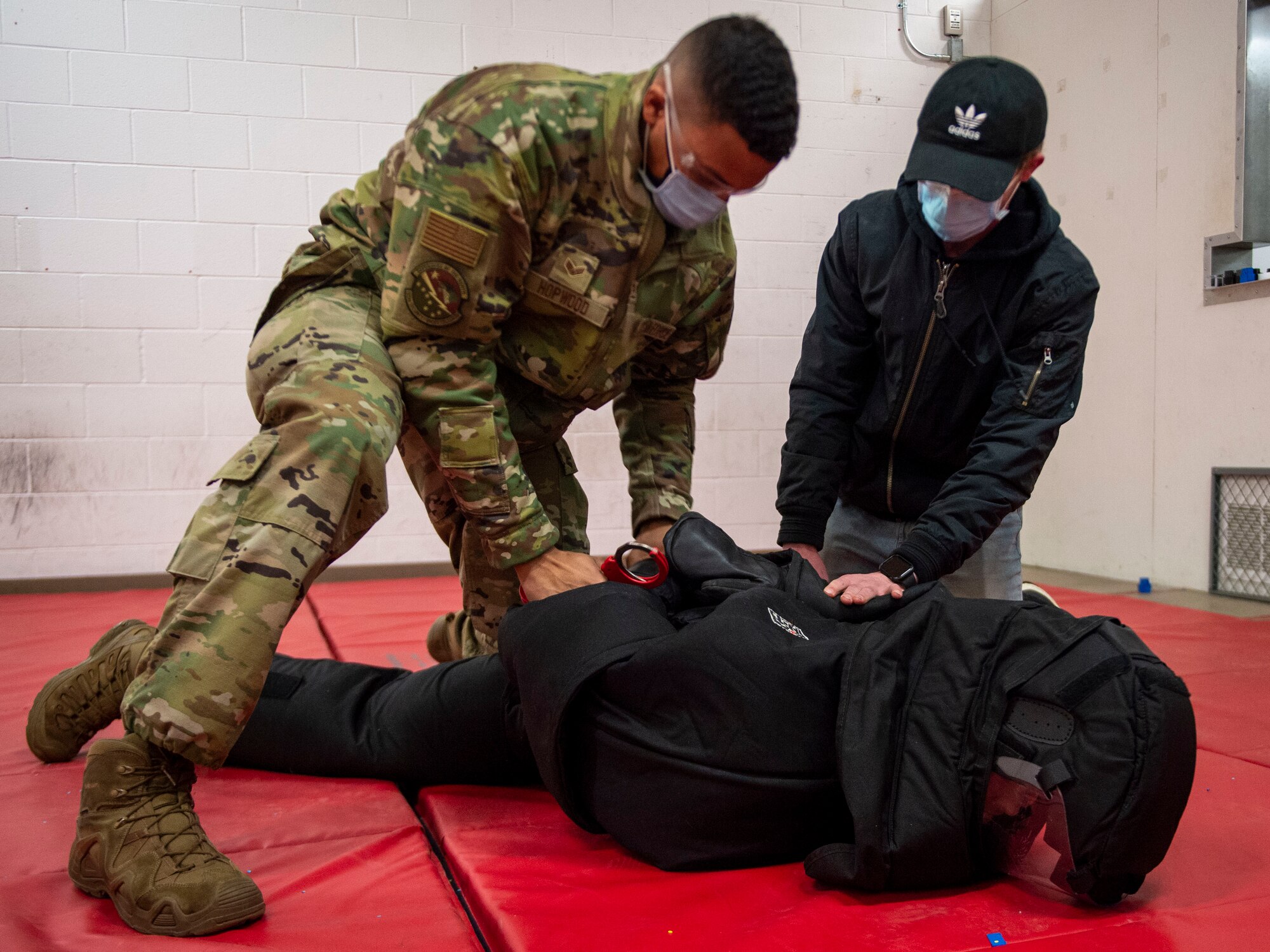 U.S. Air Force Senior Airman Jordan Hopwood, left, and Chase Kramer, right, 133rd Security Forces Squadron, put handcuffs on simulated aggressor Staff Sgt. Jeffery Fouts in St. Paul, Minn., Jan. 07, 2022.