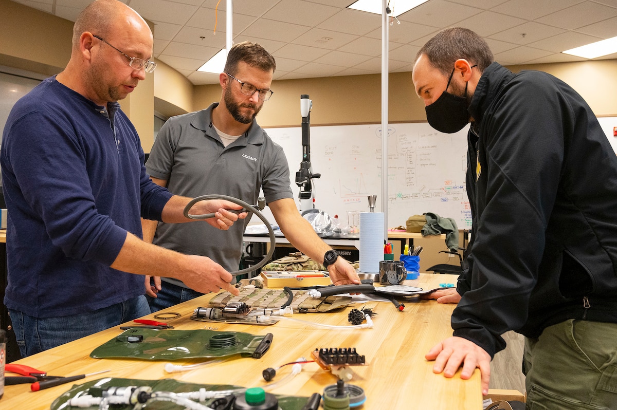 Matthew Sunday (left) and Joe Althaus (center), Wright Brothers Institute Rapid Innovation Program engineers, and Mike Moulton, an Air Force Research Laboratory engineer, work on the liquid-cooled plate carrier prototype in a lab Dec. 1, 2021. The institute and AFRL collaborated to build the prototype for testing. (U.S. Air Force photo by R.J. Oriez)