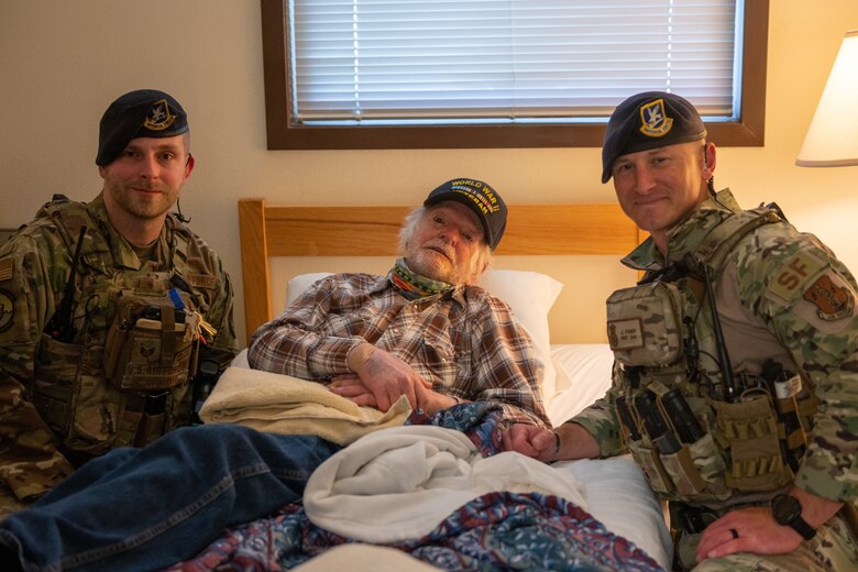 Two security forces Airmen pose with a WWII vet.