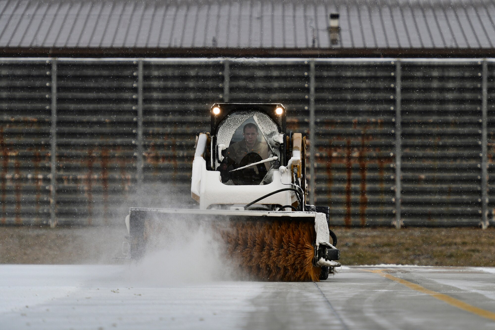 An Airman removes snow on the flightline.