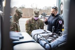 Pvt. Aduyel Kusi, right, and Spc. Jake Casucci practice loading a wheeled-stretcher into an ambulance in Brockton, Mass., Dec. 28, 2021. The Massachusetts National Guard members are providing non-clinical assistance at medical facilities across the commonwealth during a COVID-19 surge.