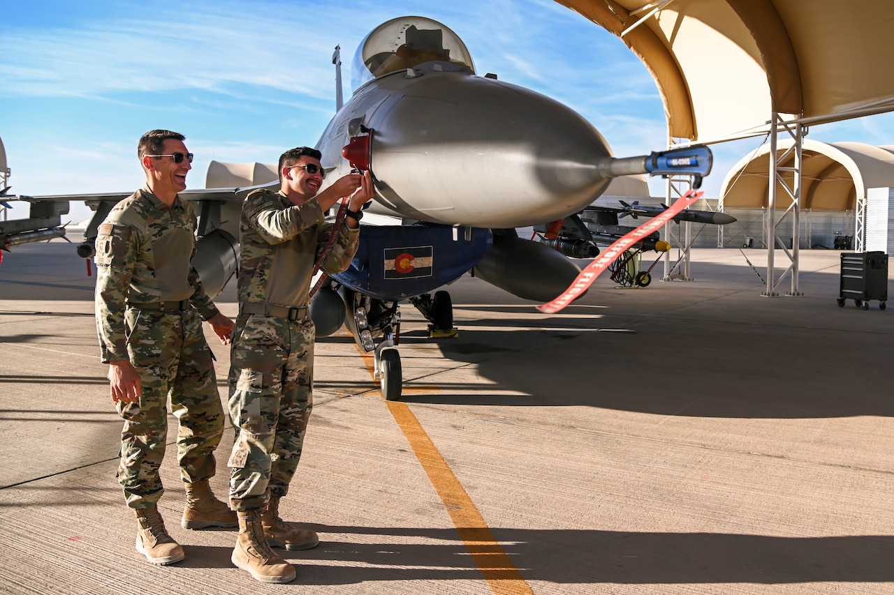 Two airmen inspect an aircraft.