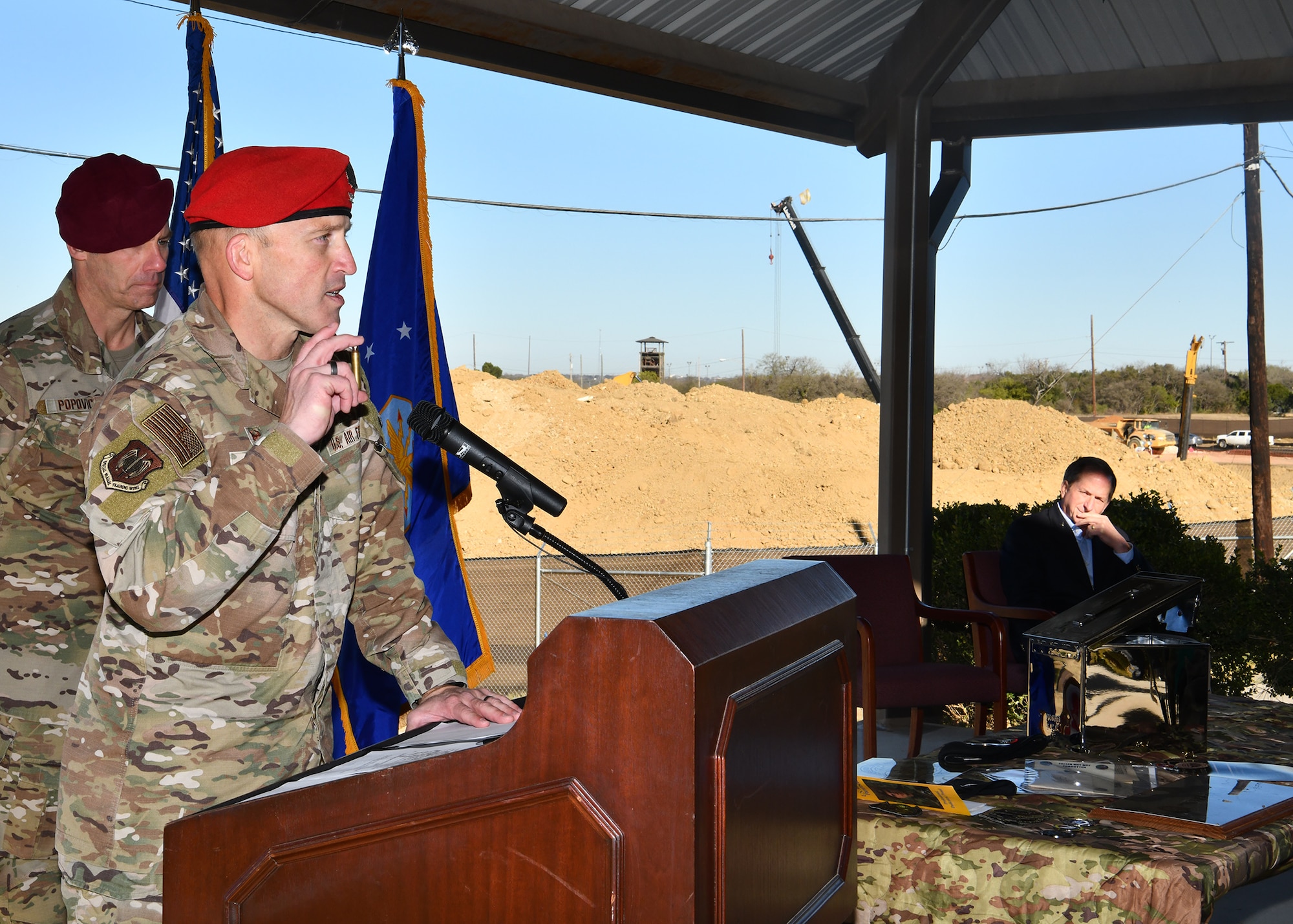 U.S. Air Force Col. Mason R. Dula (center left), Special Warfare Training Wing commander, holds a spent bullet shell prior to placing it in a time capsule while standing in front of the future site of the SWTW aquatics training facility as U.S. Air Force Command Chief Master Sgt. Todd M. Popovic (left) and former U.S. Air Force Chief of Staff Gen. David Goldfein (ret.) listens