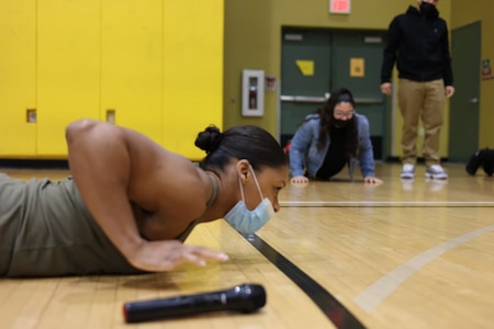 woman performing pushups on a gym floor.
