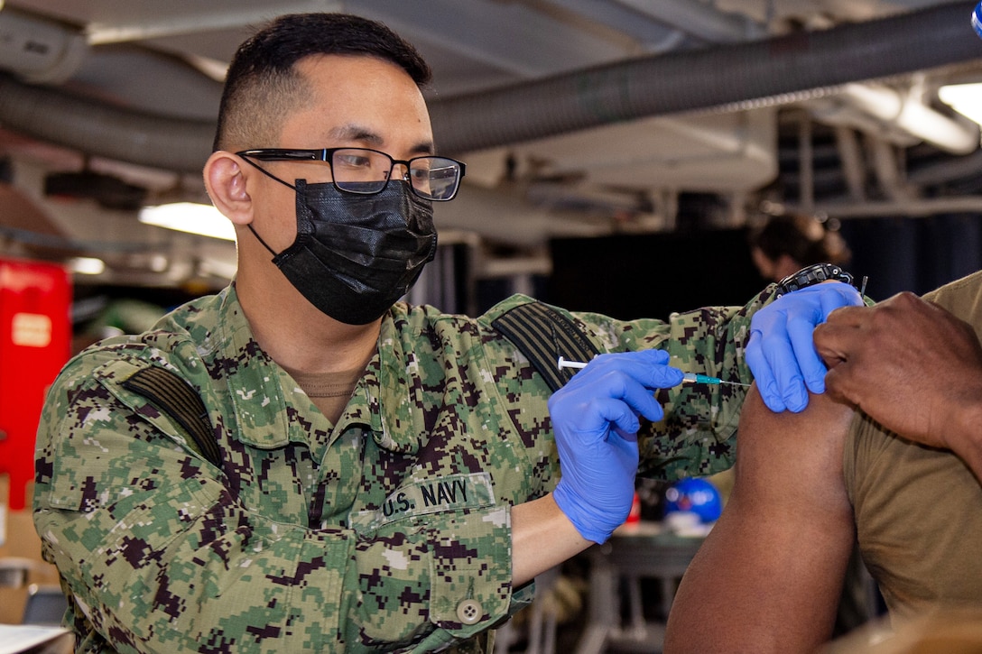 A sailor prepares to give another sailor a vaccine.