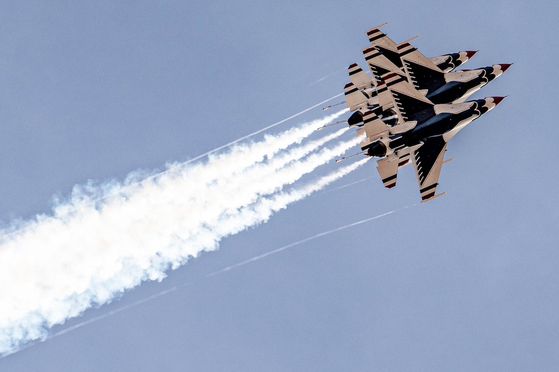 Three fighter jets fly in close formation.