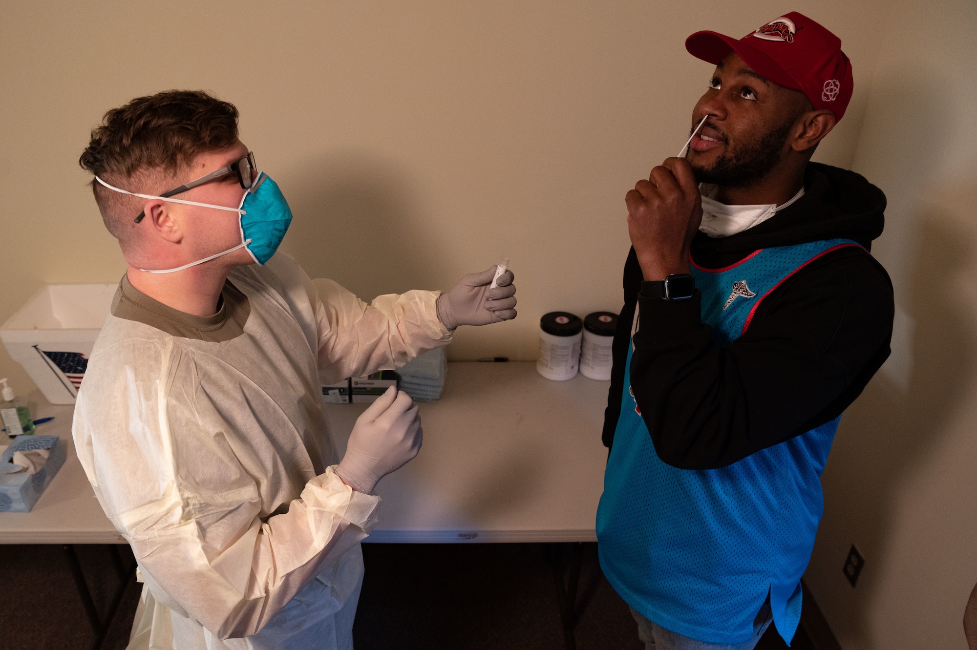 U.S. Air Force Staff. Sgt. Bradley Borytsky, 51st Operational Medical Readiness Squadron mental health technician, demonstrates to Staff Sgt. Aaron Wynn, 51st Medical Support Squadron NCO in charge of the medical equipment office, how to properly swab his nose for an antigen test at Osan