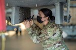 An airman wearing a face mask works on an aircraft.