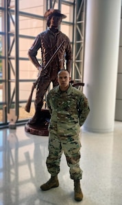 An Air Force Officer is standing in front of a minuteman statue indoors.