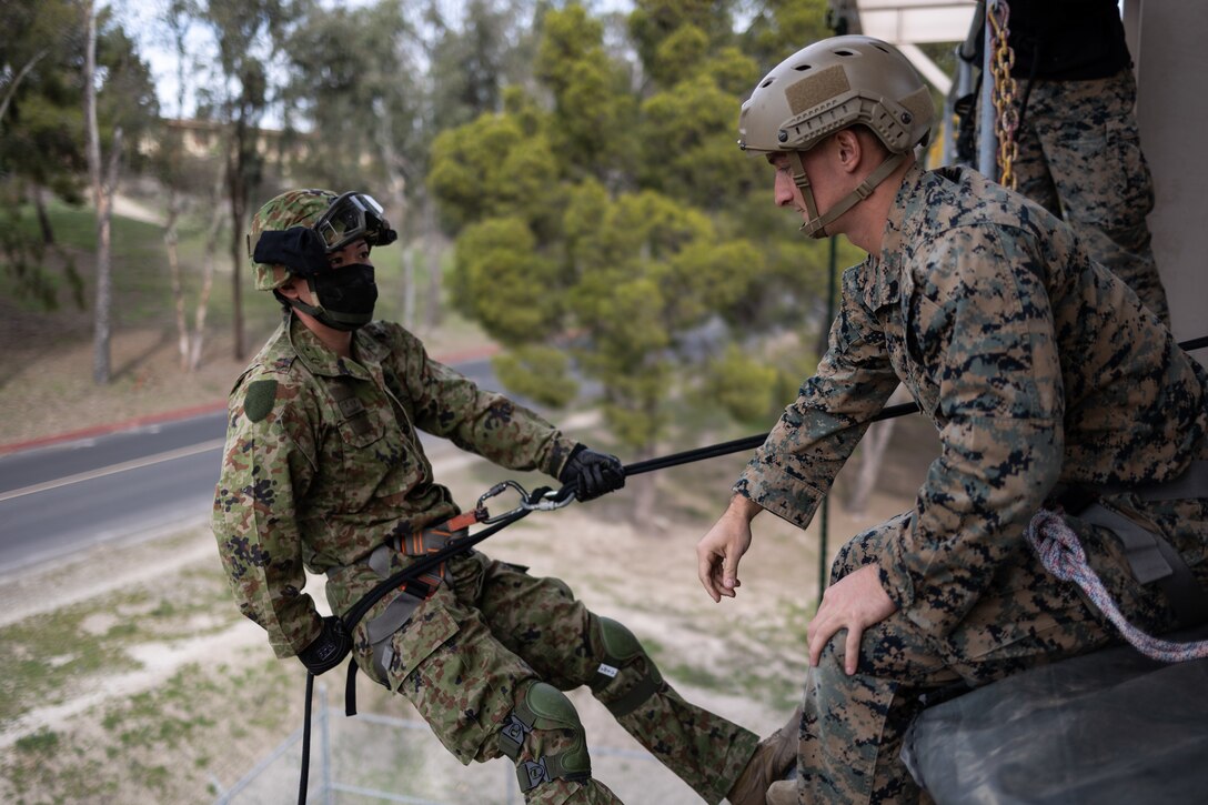 U.S. Marine Corps Sgt. Dylan Bryan, a helicopter rope suspension techniques master with 1st Air Naval Gunfire Liaison Company, assists a Japan Ground Defense Force (JGSDF) soldier with 2nd Amphibious Rapid Deployment Regiment to fast-rope from a rappel tower during exercise Iron Fist 2022 at Marine Corps Base Camp Pendleton, California, Jan. 12, 2022. For almost two decades the U.S. Marine Corps, U.S. Navy, and JGSDF have conducted exercise Iron Fist, training together in amphibious operations and affirming the U.S. commitment to our allies. (U.S. Marine Corps photo by Cpl. Garrett Kiger)