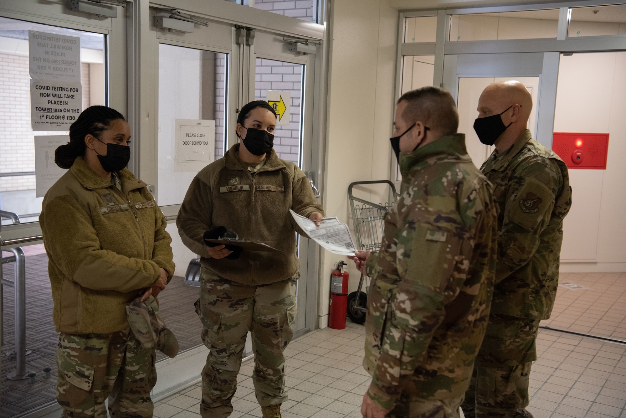 Military members stand in a circle in the lobby of the contingency dorms.