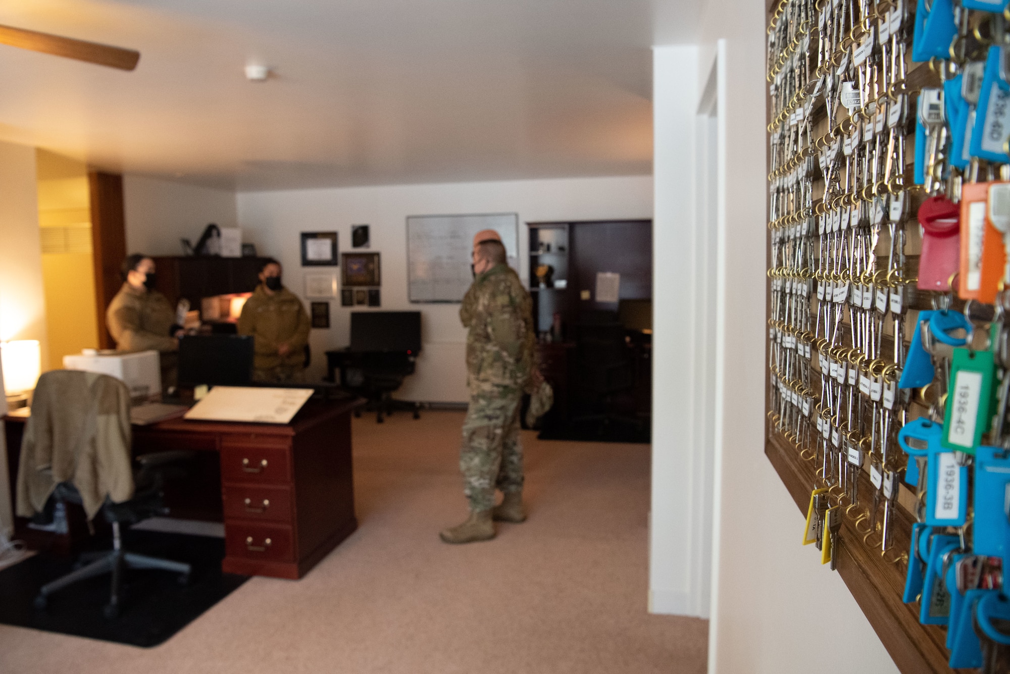 Military members stand in an office talking..