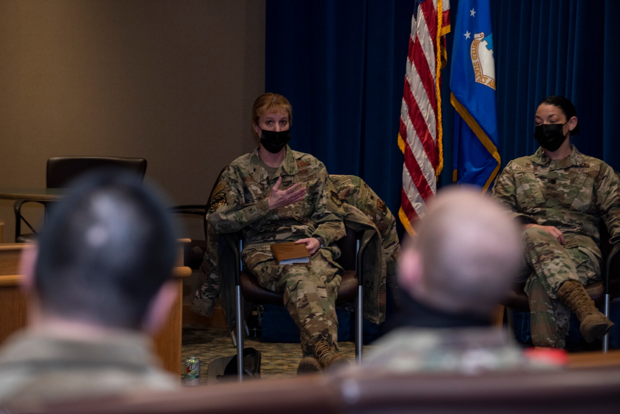 Colonel address crowd as two attendees look on.