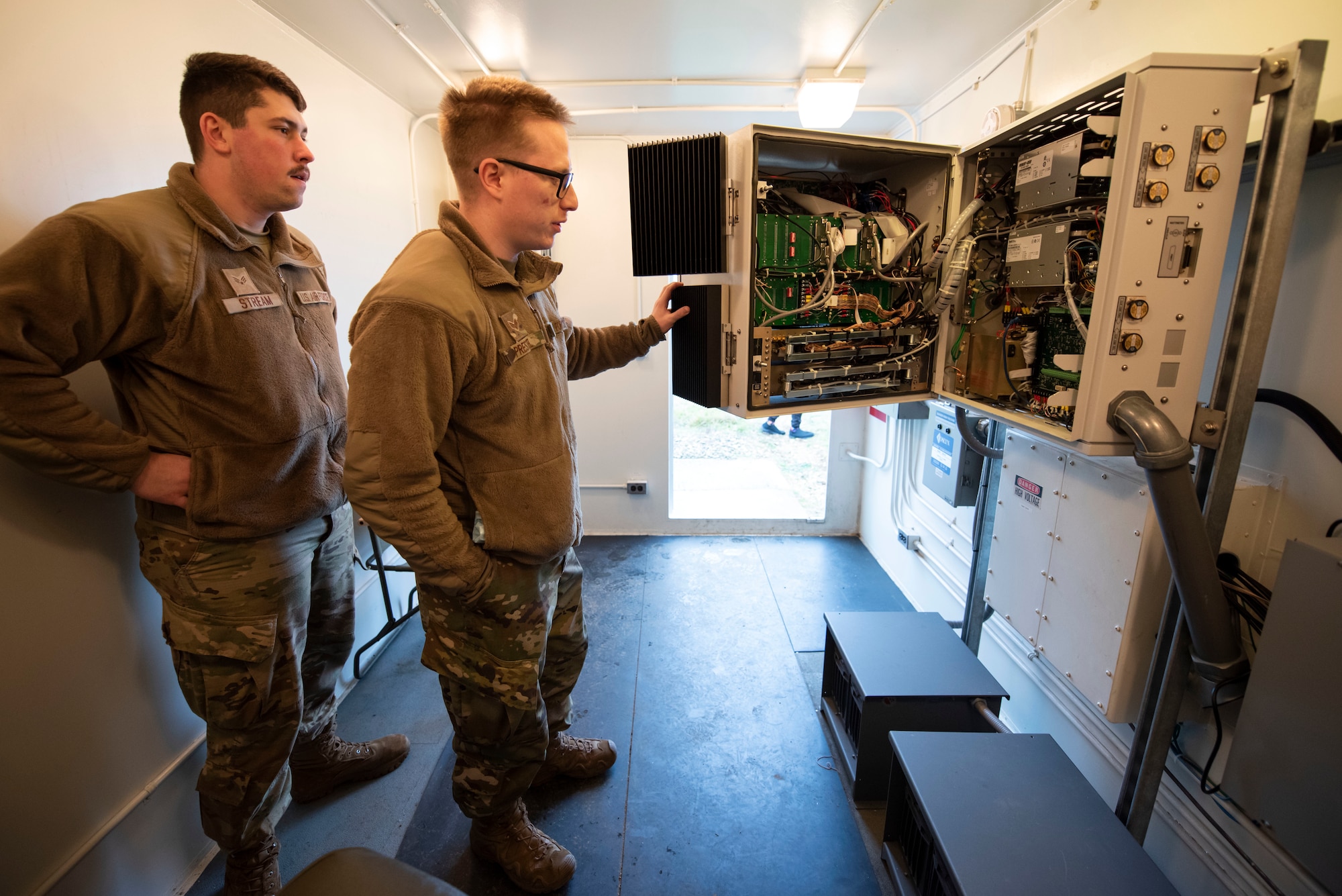 U.S. Air Force Senior Airmen Alex Prestel and Jarrett Stream, 420th Expeditionary Air Base Squadron radar airfield and weather systems (RAWS) technicians, open a transmitter cabinet at Royal Air Force Fairford, England, Jan. 11, 2022. Members of the 420th EABS, deployed from around the world, work  together with the 420th Air Base Squadron to support various missions at Fairford. From Jan. 8-12, the 420th EABS provided support for the 352nd Special Operations Wing’s Agile Combat Employment exercise. ACE exercises prepare Airmen to operate effectively from locations with varying levels of capacity and support. (U.S. Air Force photo by Senior Airman Jennifer Zima)