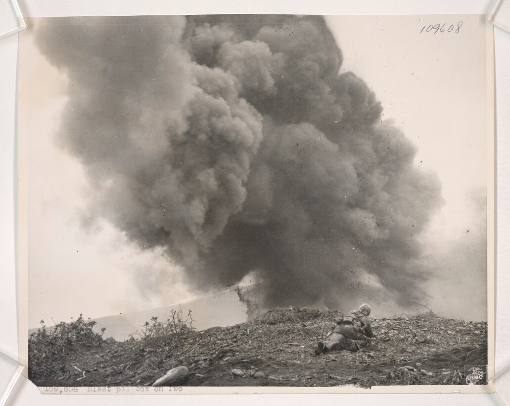 A Marine Combat Engineer sets off a satchel charge that blasts a Japanese defensive position on Iwo To, Japan, during the Battle of Iwo Jima, Feb. 25, 1945. Many of these positions had to be destroyed to prevent the enemy from returning to their shelters and open fire on the Marine flanks.