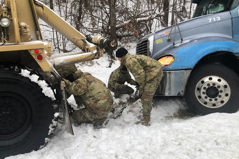 Soldiers help a stranded motorist in the snow.