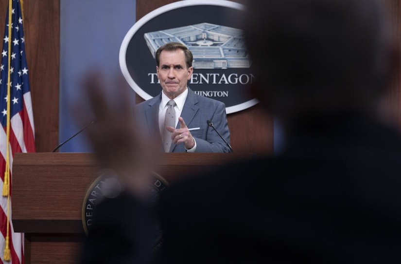 A man briefs during a socially distant news conference. There is a sign behind him indicating he is at the Pentagon.