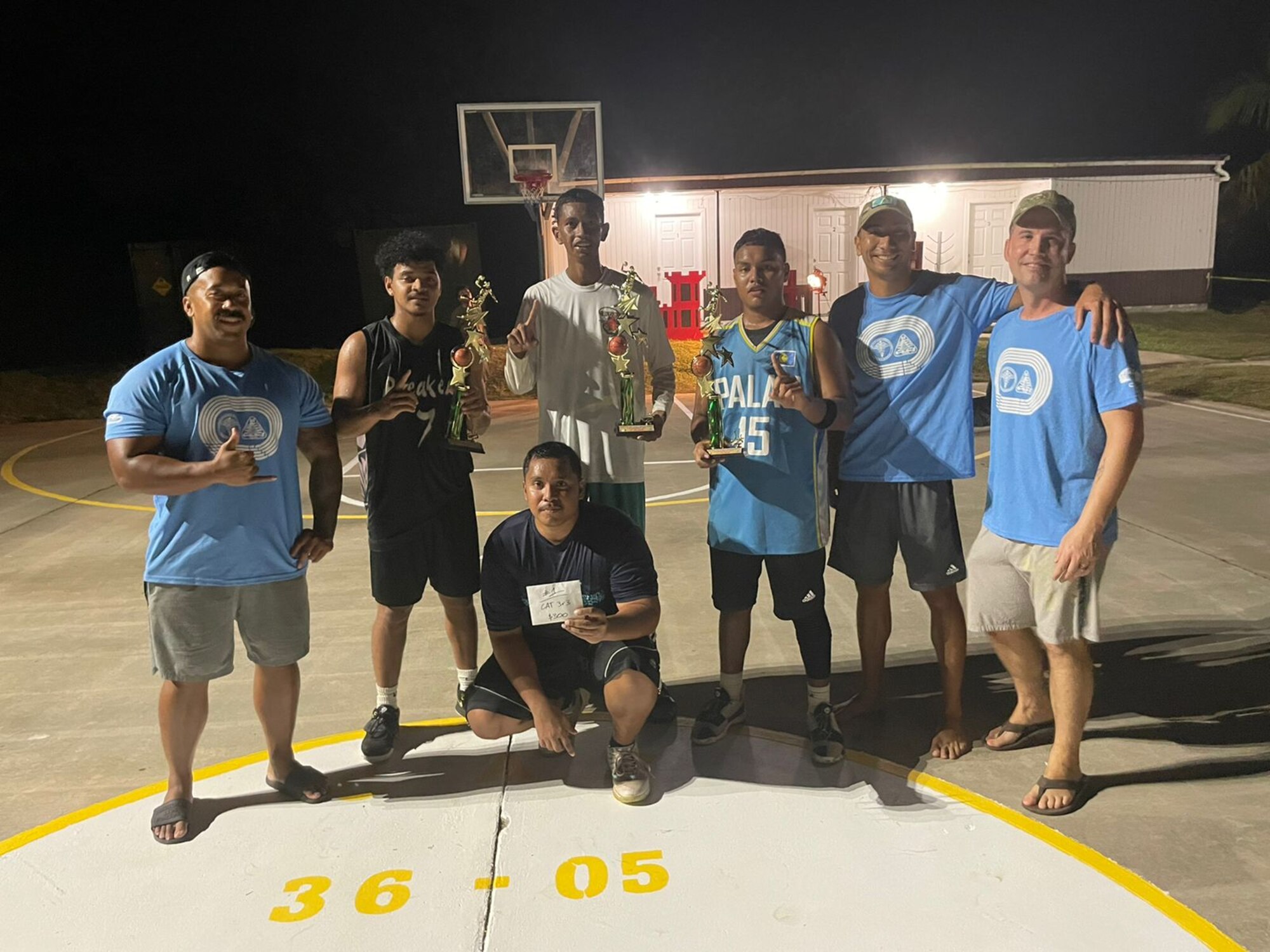 Members from the Civic Action Team- Palau stand with locals during a basketball tournament. The CAT is a tri-service deployment to Palau that has been running for over 50 years. The team is from the 36th Civil Engineering Squadron and they have 6 main objectives; Community Construction Projects, Community Relations Projects, Monument Maintenance, Apprenticeship Program, Medical Care and Camp Maintenance. (Courtesy Photo)