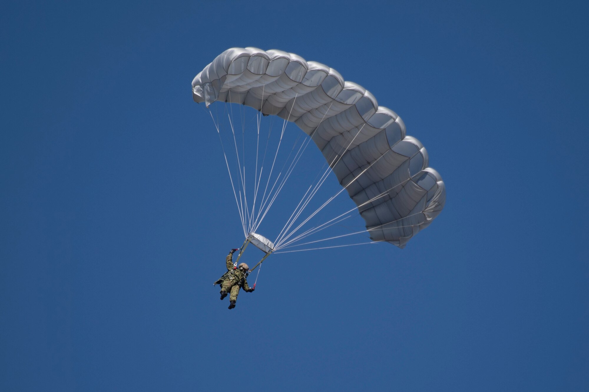A Japanese paratrooper with a deployed parachute floats to a landing