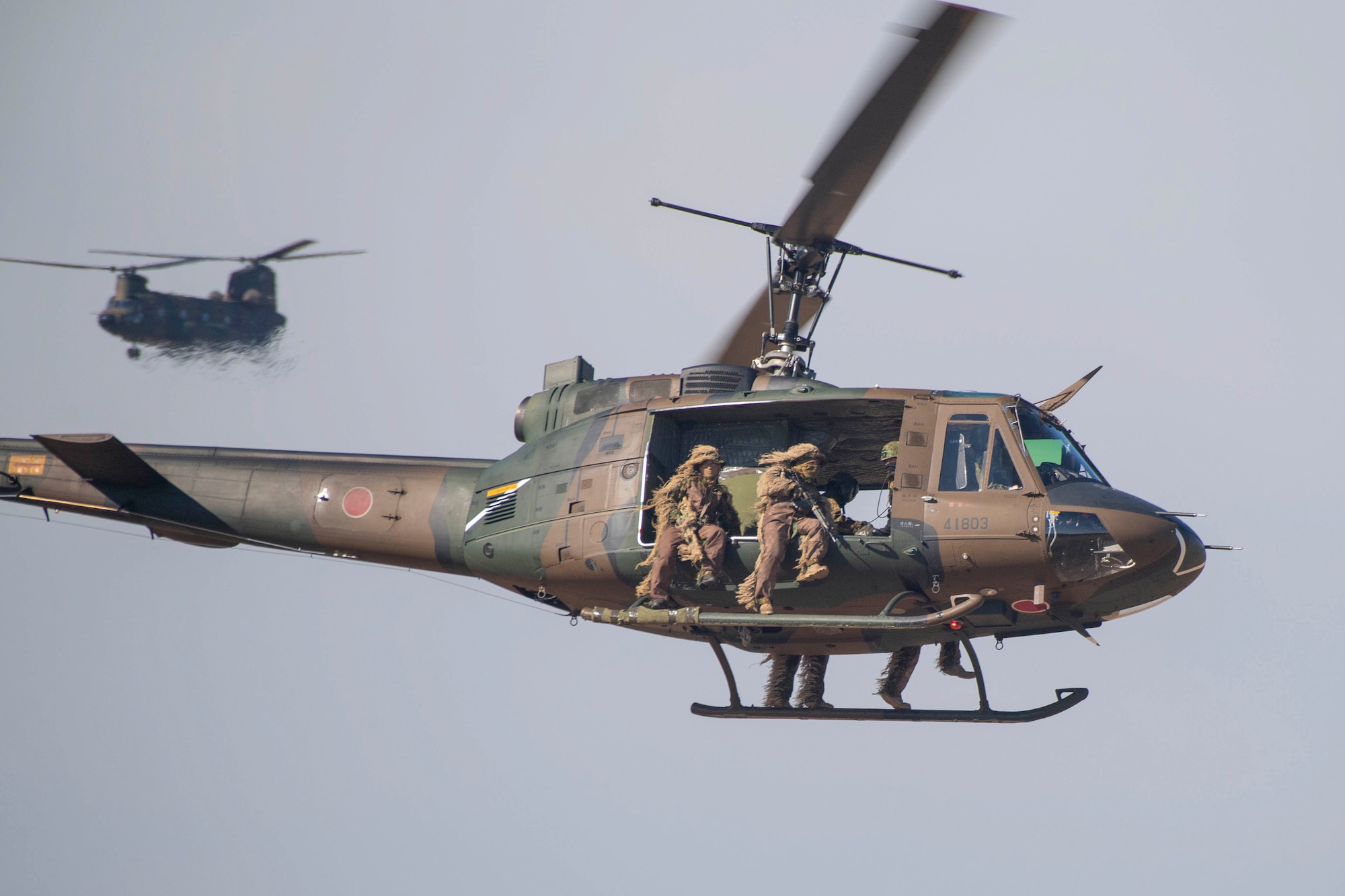 Japanese soldiers fly in a helicopter over a paratrooper drop zone