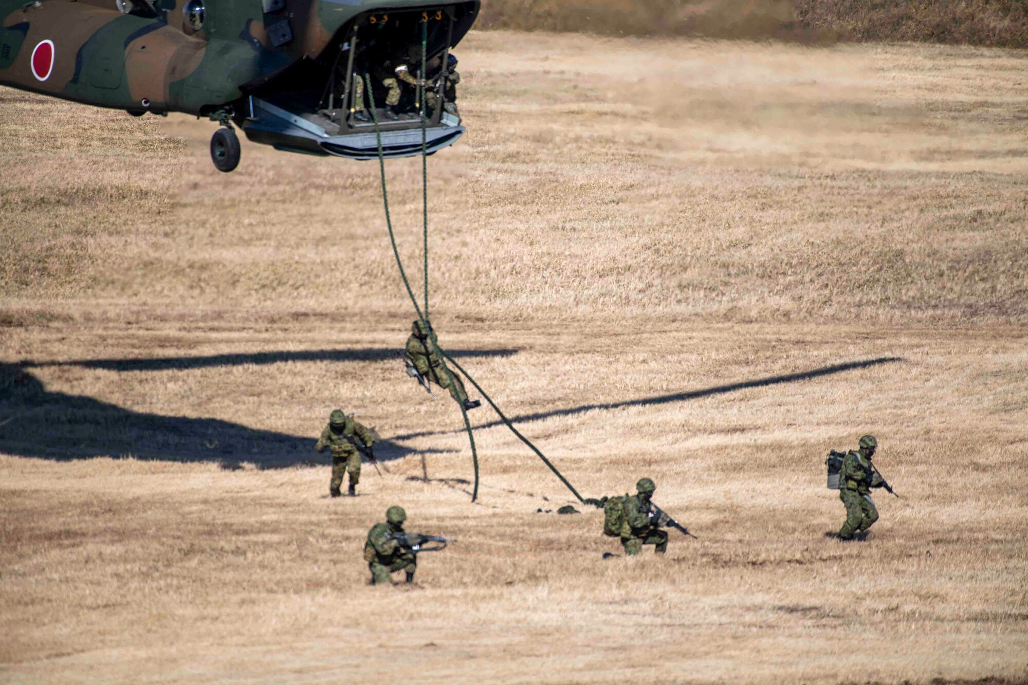 Five Japanese paratroopers jump out the back hatch of a Chinook helicopter