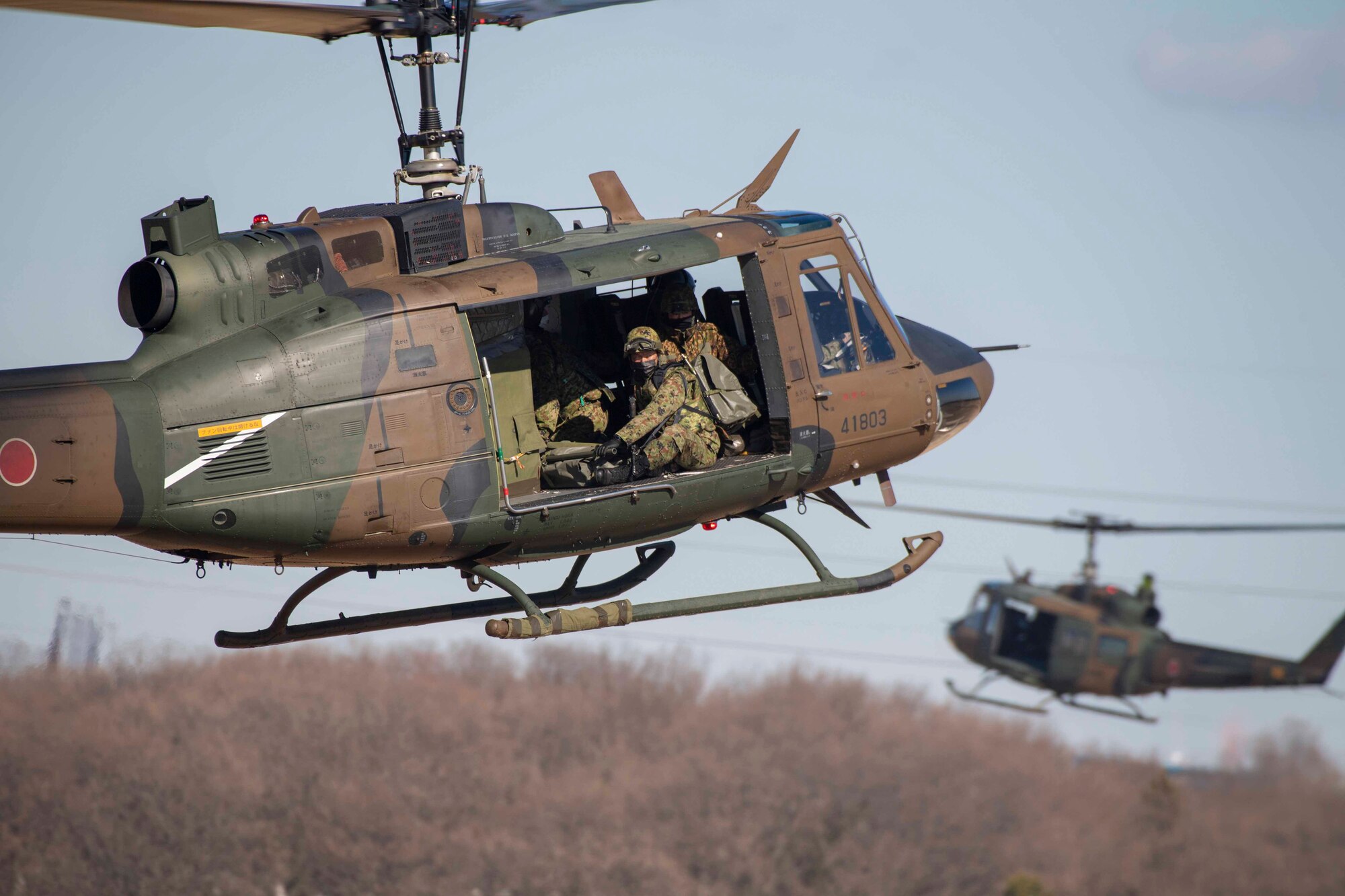 A Japanese paratrooper hangs out of a helicopter