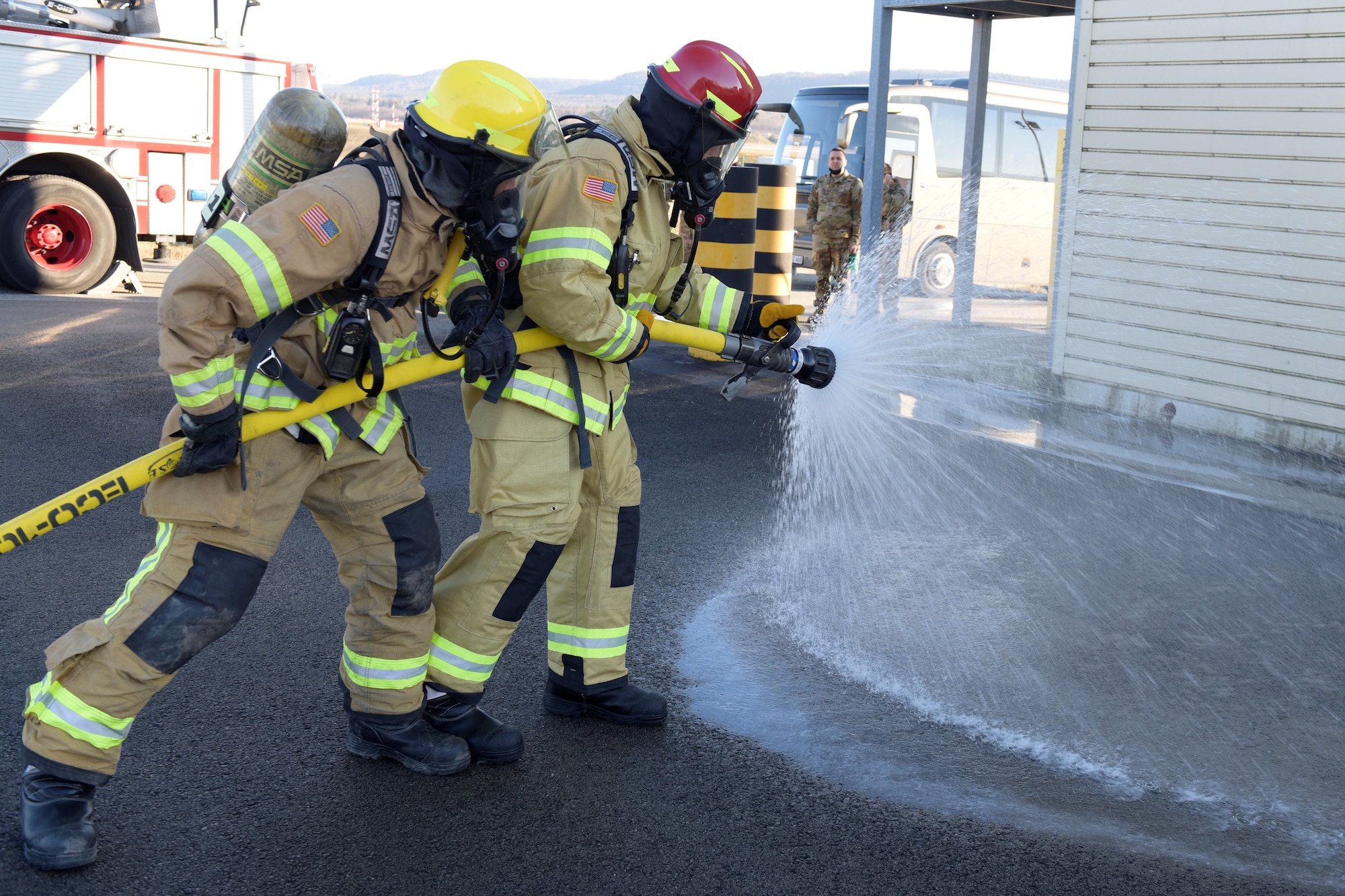 Two men use a fire hose
