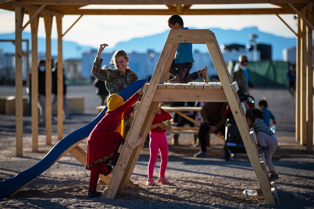 An Air Force officer plays with Afghan children on a slide.