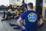 Petty Officer 3rd Class Noah Denend (foreground) watches as his shipmates demonstrate ground escape procedures during law enforcement training at Coast Guard Station Chincoteague, Virginia, February 18, 2020. The new Coast Guard training adds a focus on ground fighting in order to keep law enforcement officers safe as they adapt to ever-changing situations. (U.S. Coast Guard photo by Petty Officer 1st Class Stephen Lehmann)