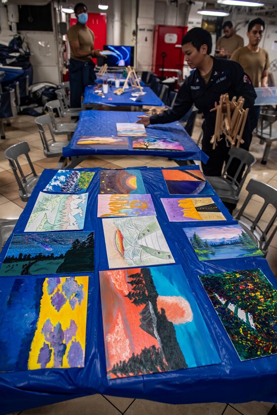 Paintings sit out on long tables.
