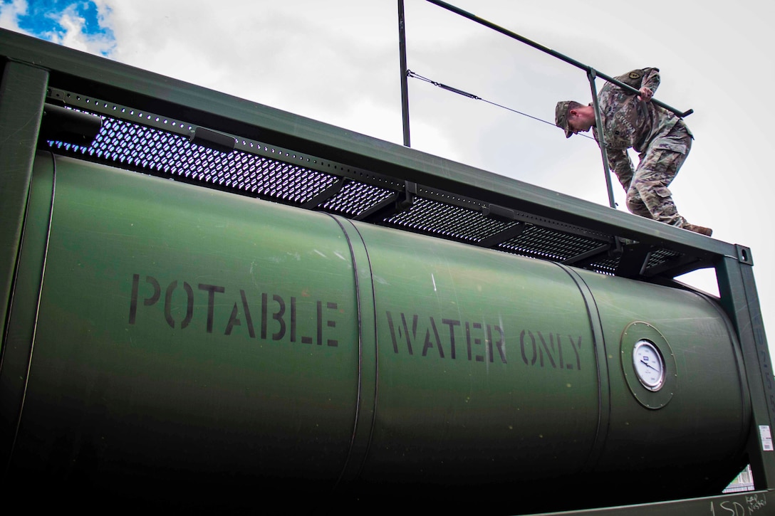 A soldier opens a potable water tank hatch.