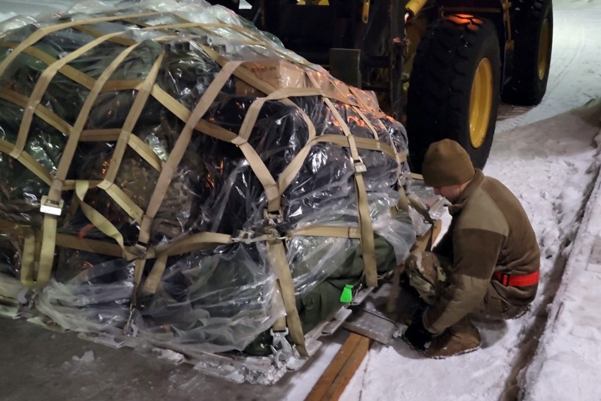 Alaska Air National Guard Master Sgt. Joshua Moore, 168th Logistics Readiness Squadron, loads cargo Jan. 12, 2022, on a 211th Rescue Squadron HC-130J Combat King II at Joint Base Elmendorf-Richardson, Alaska. The HC-130 was carrying 20 Alaska National Guard Soldiers and Airmen to Yakutat in response to a weather disaster. (U.S. Air Force courtesy photo by Master Sgt. Serjio Cerda)