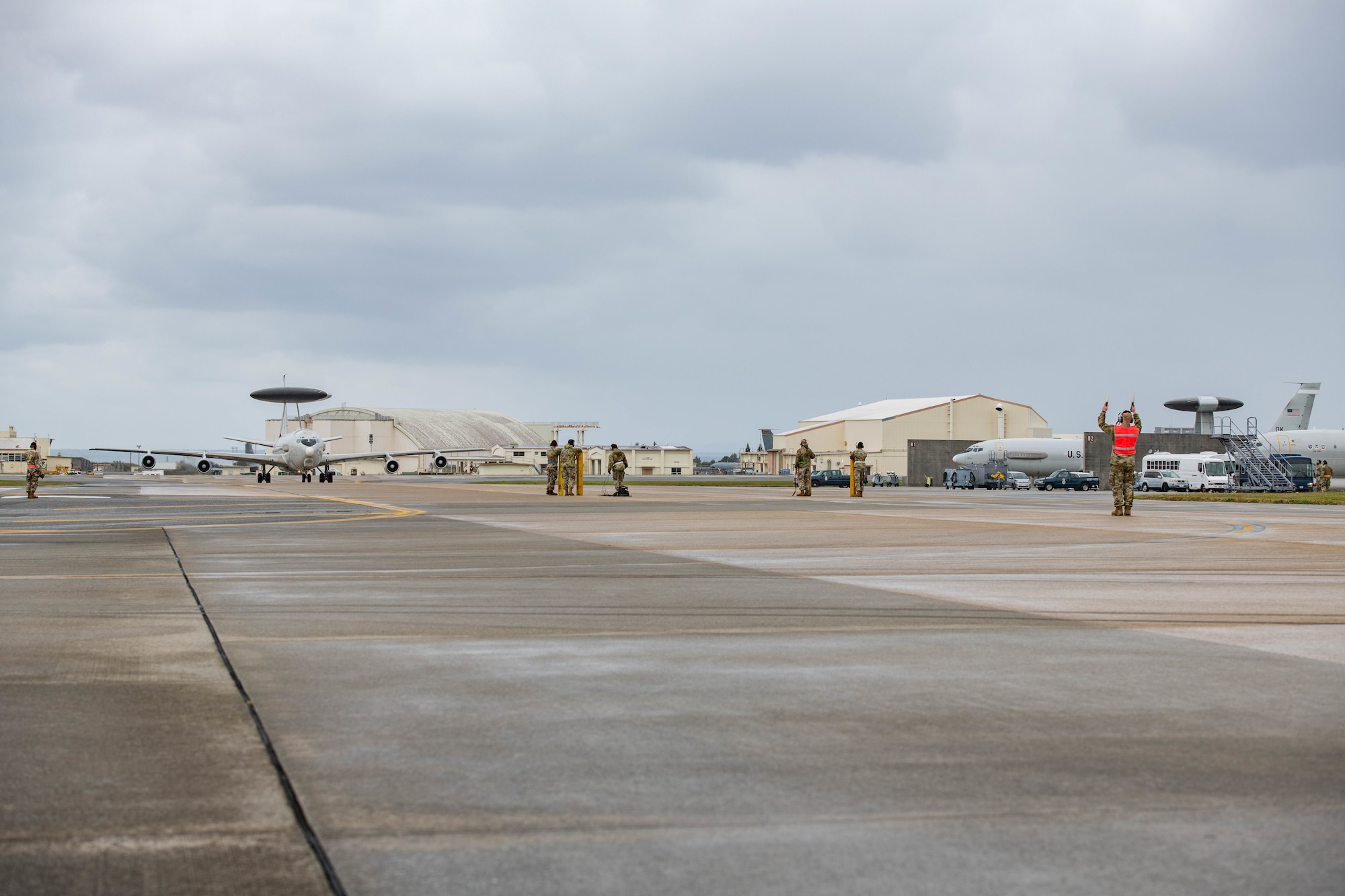 A plane taxis towards airmen on the flight line