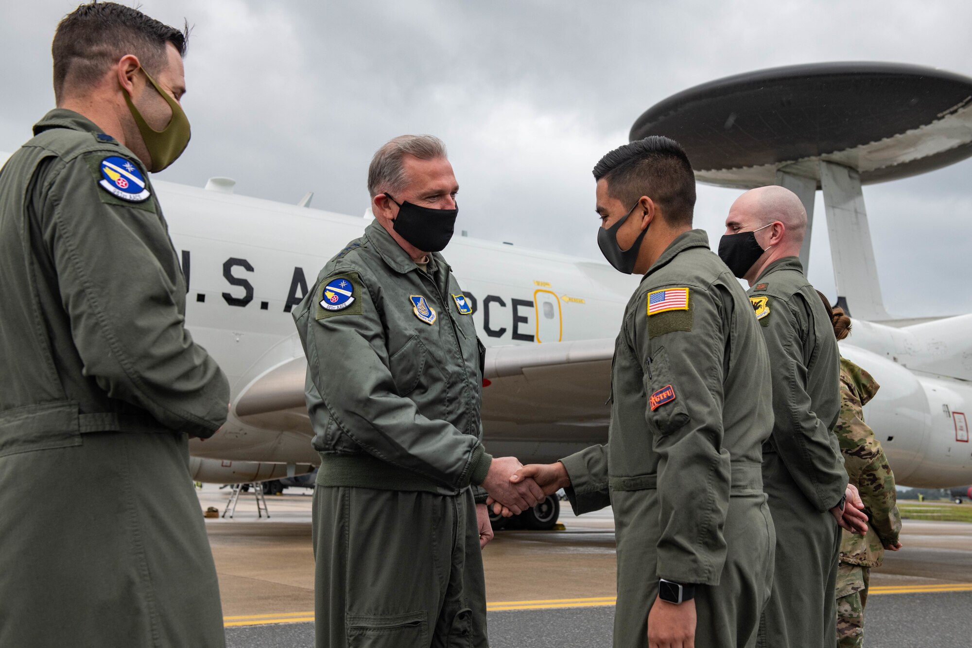 A general coins and shakes hands with an airman