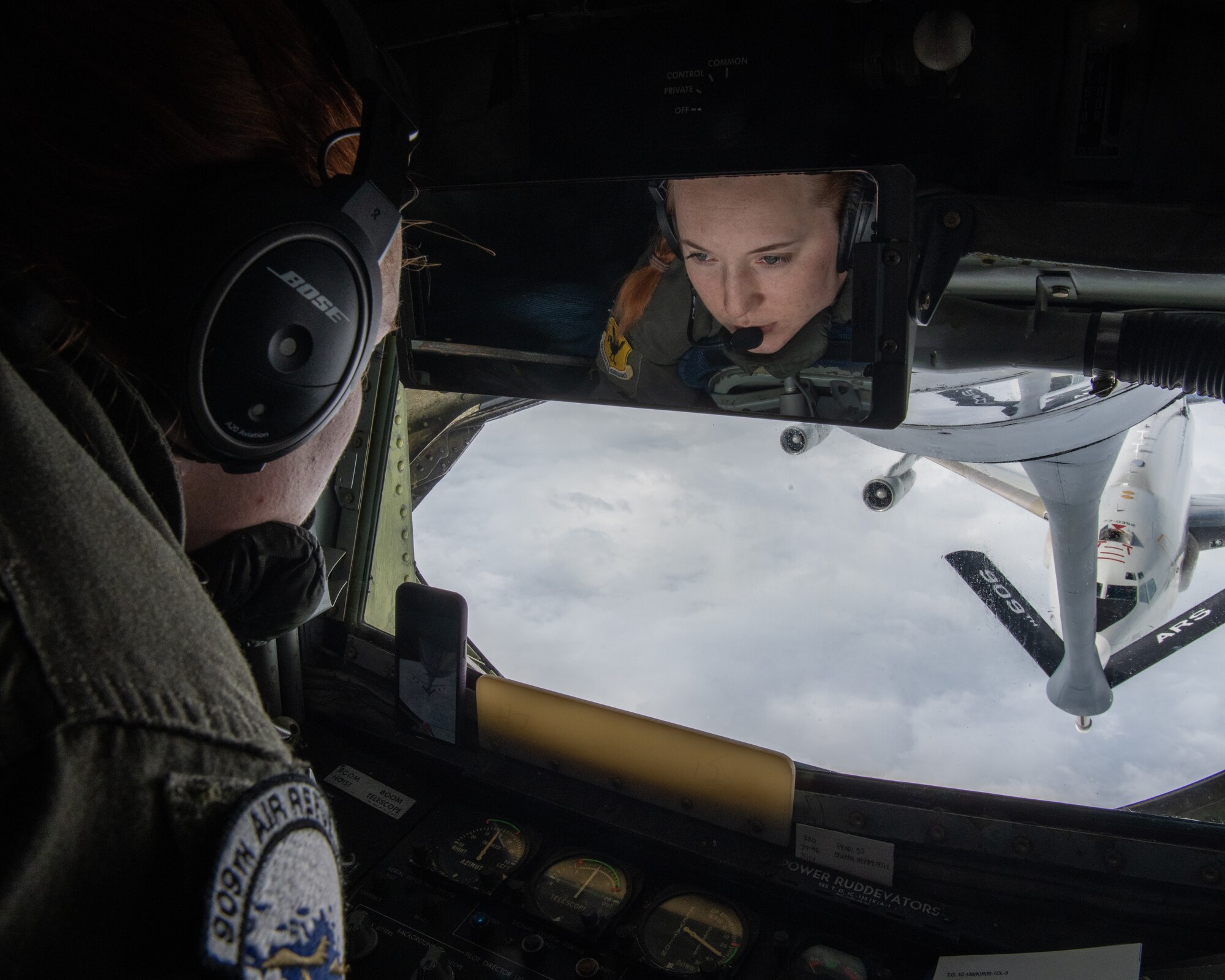 U.S. Air Force Staff Sgt. Samantha Grendahl, 909th Air Refueling Squadron boom operator, prepares to refuel an approaching U.S. Air Force E-3G Sentry over the Pacific Ocean