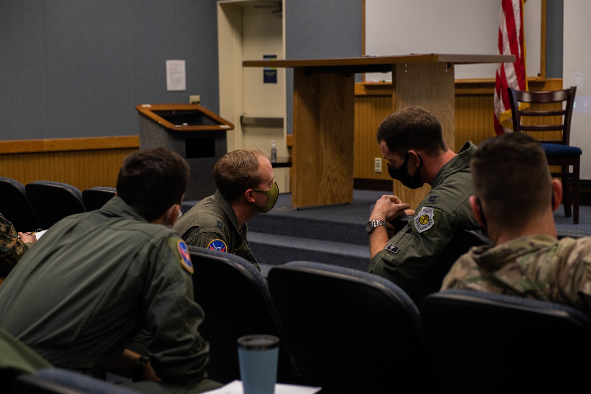 A bunch of seated military members discuss an exercise