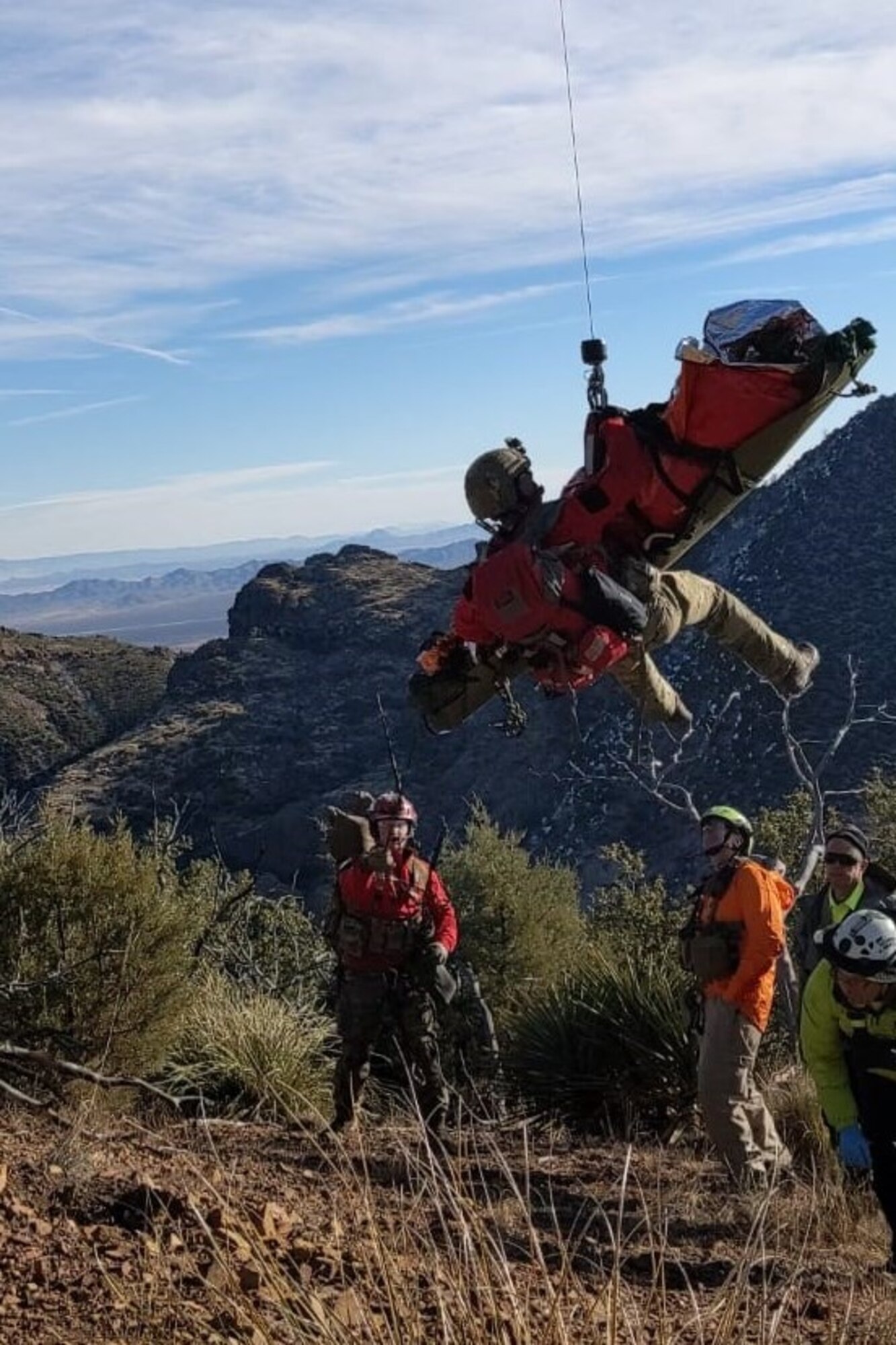 A pararescuemen is hoisting a patient into an HH-60