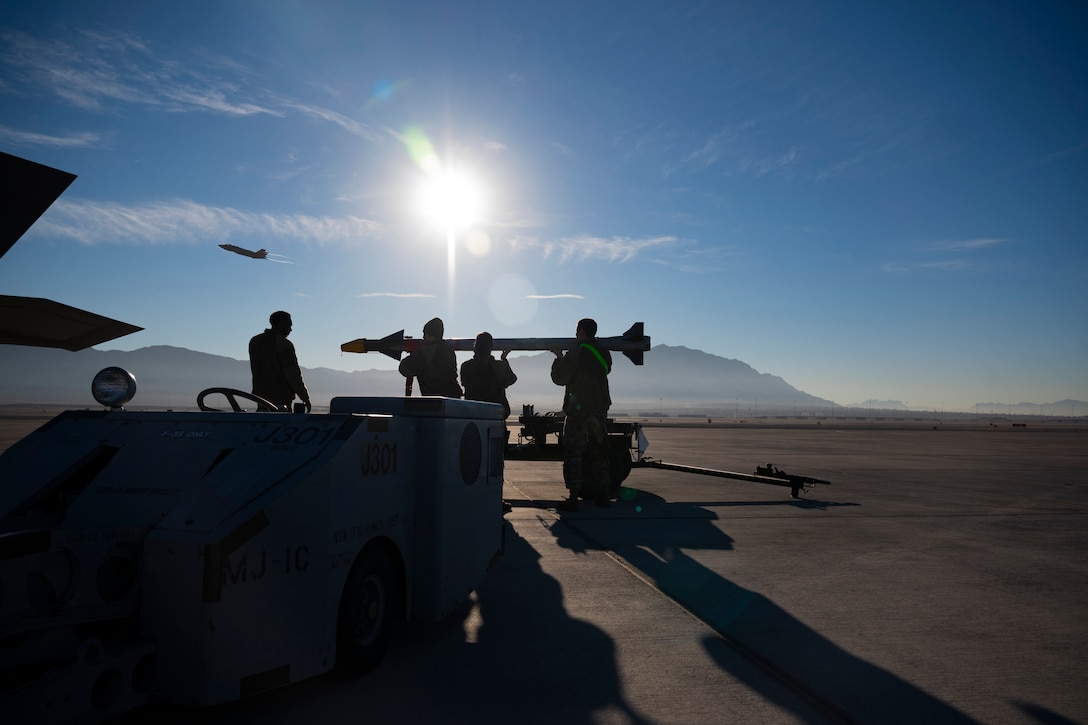 Two airmen prepare to load a missile onto a military aircraft.