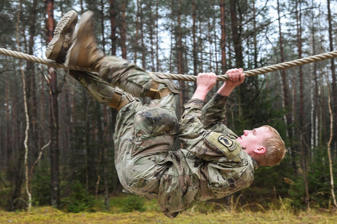 A paratrooper hangs onto a rope.