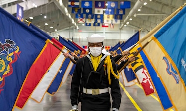 Sailors graduating from boot camp march in Midway Ceremonial Drill Hall during a pass-in-review graduation ceremony at Recruit Training Command.