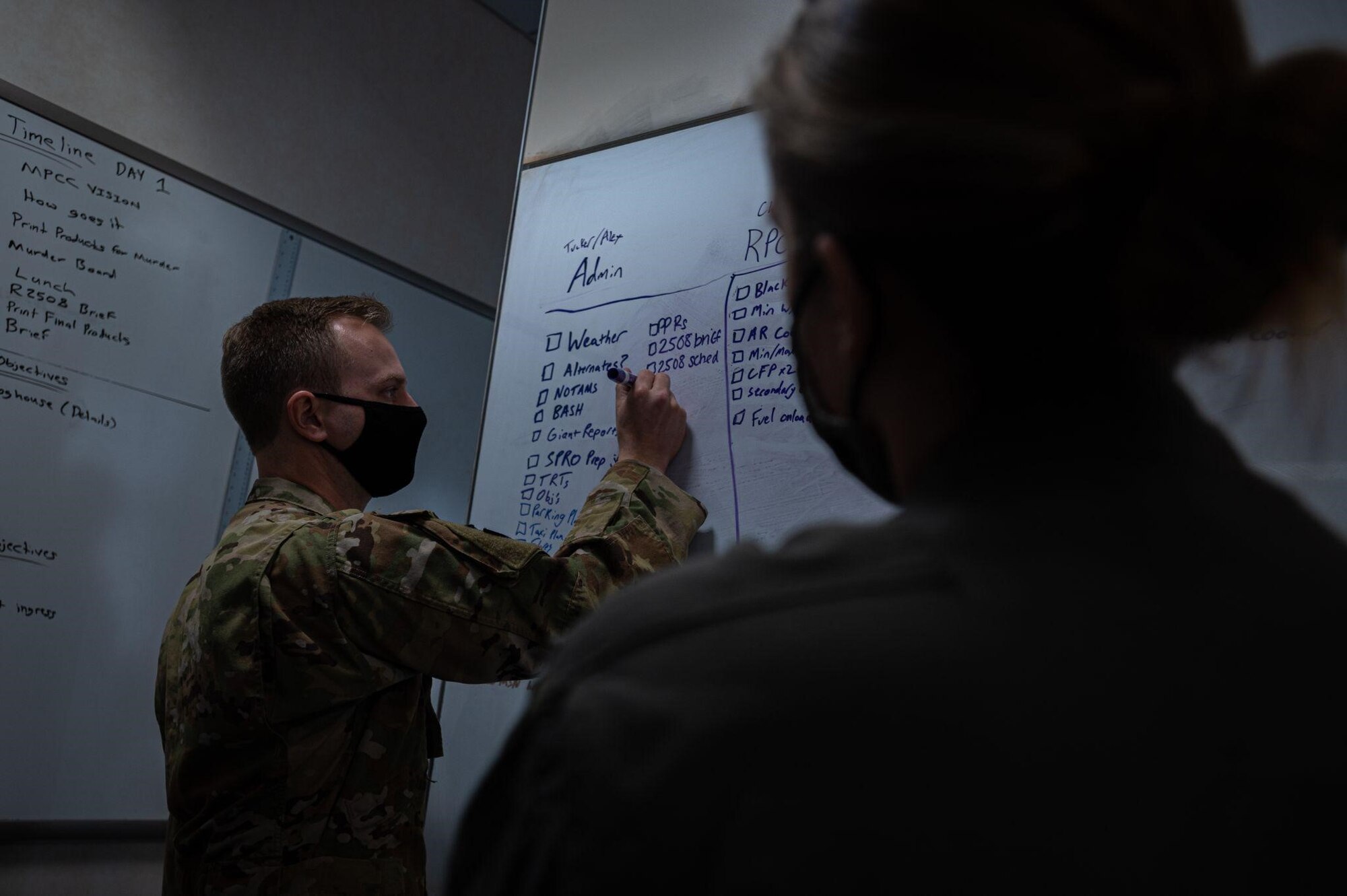 Man writes on whiteboard as woman supervises